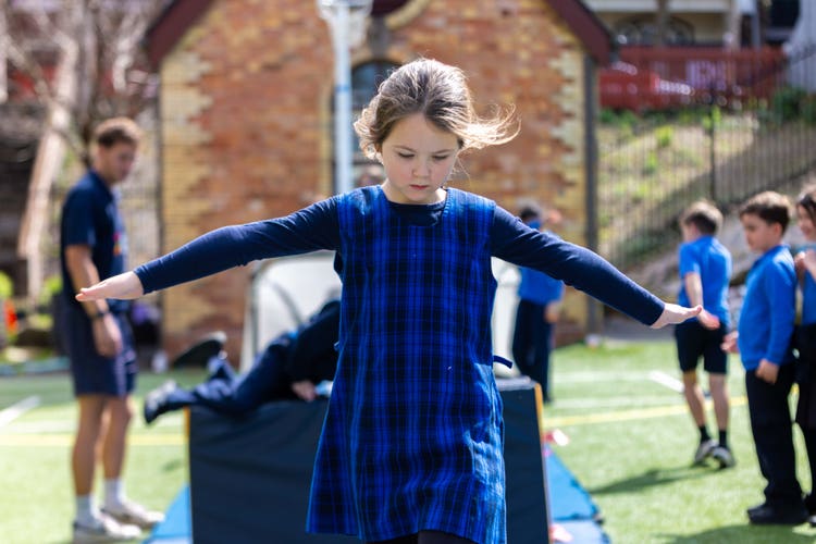 student on the balancing beam oustide in the playground during a gymnastics lesson